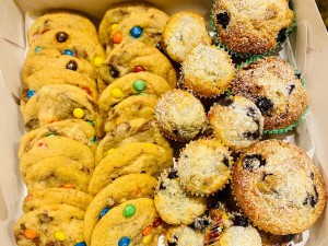 A full box of M&M cookies and berry cupcakes.